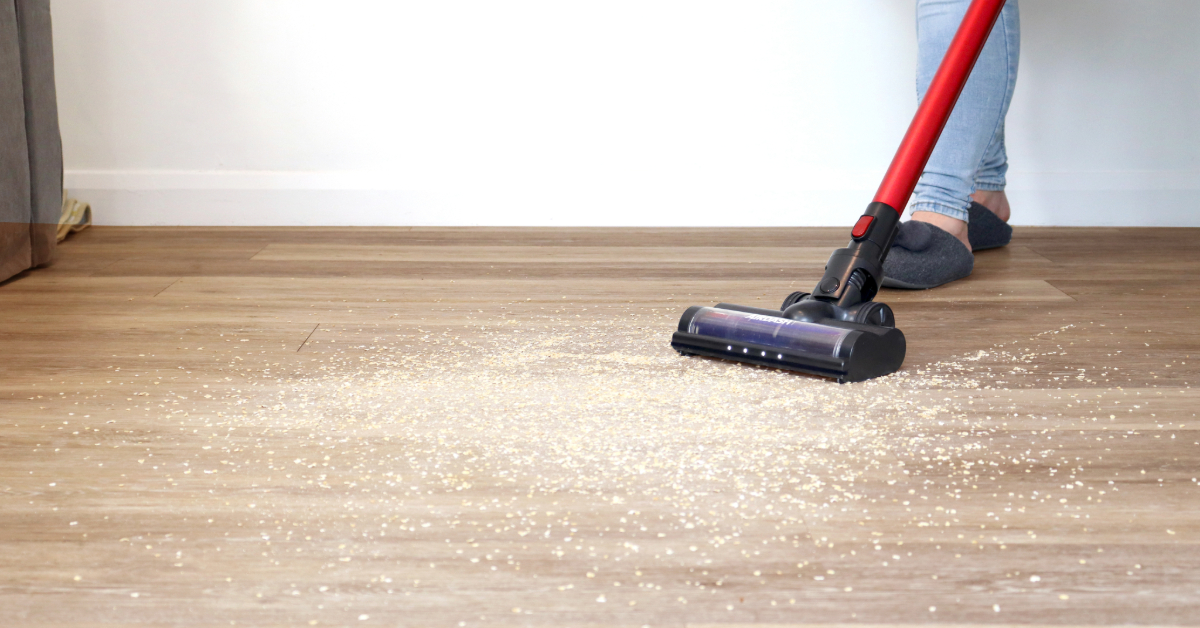 A person vacuuming a wood floor